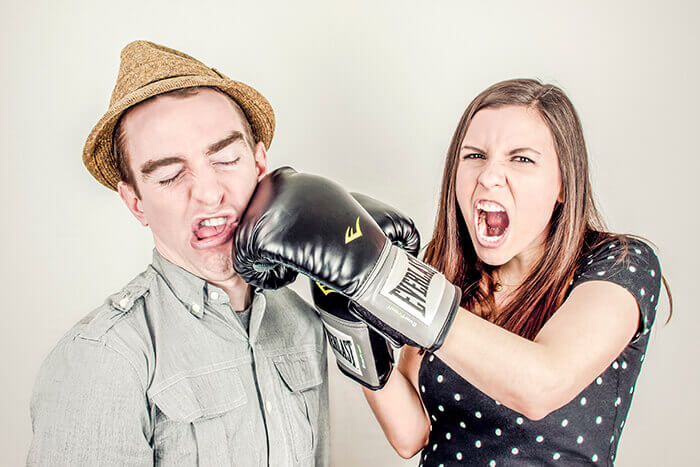 A woman wearing boxing gloves pretending to punch a man in the face