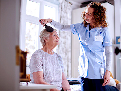 In-home caregiver brushing lady's hair