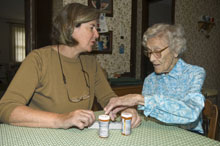 caretaker helping elderly woman with medicine