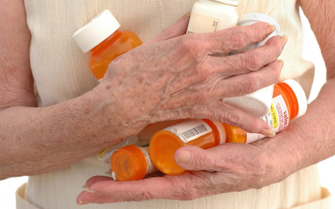 Elderly person holding pill bottles